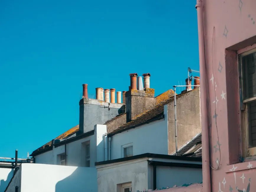 A picturesque view of urban rooftops featuring chimneys against a clear blue sky.